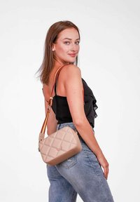 Beige prošívaná taška přes tělo s hladkým povrchem, která má vícebarevný nastavitelný popruh a obdélníkový tvar.
