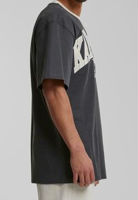Dark gray cotton t-shirt featuring short sleeves, a crew neckline, and bold white lettering "KARL" on the front. Smooth texture.