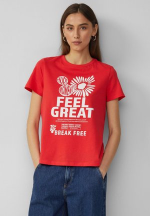 Red short-sleeve t-shirt featuring white graphic text and flower designs. Material appears smooth; shirt has a relaxed fit with a crew neck.