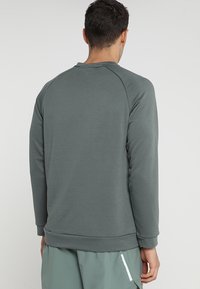 Szary sweatshirt z okrągłym dekoltem i rękawami raglanowymi, z ribbowanymi mankietami i dołem, wykonany z miękkiego materiału, o gładkiej fakturze bez wzorów.