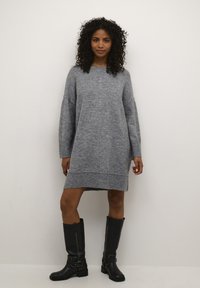 Grijs gebreid sweaterjurk met lange mouwen, geribbelde zoom en een relaxte pasvorm. Draag het met kniehoge zwarte leren laarzen met gespen.