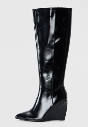 Stivali in pelle nera con tacco a zeppa, al ginocchio, dalla punta affilata e dalla finitura liscia, caratterizzati da un design elegante e affusolato.