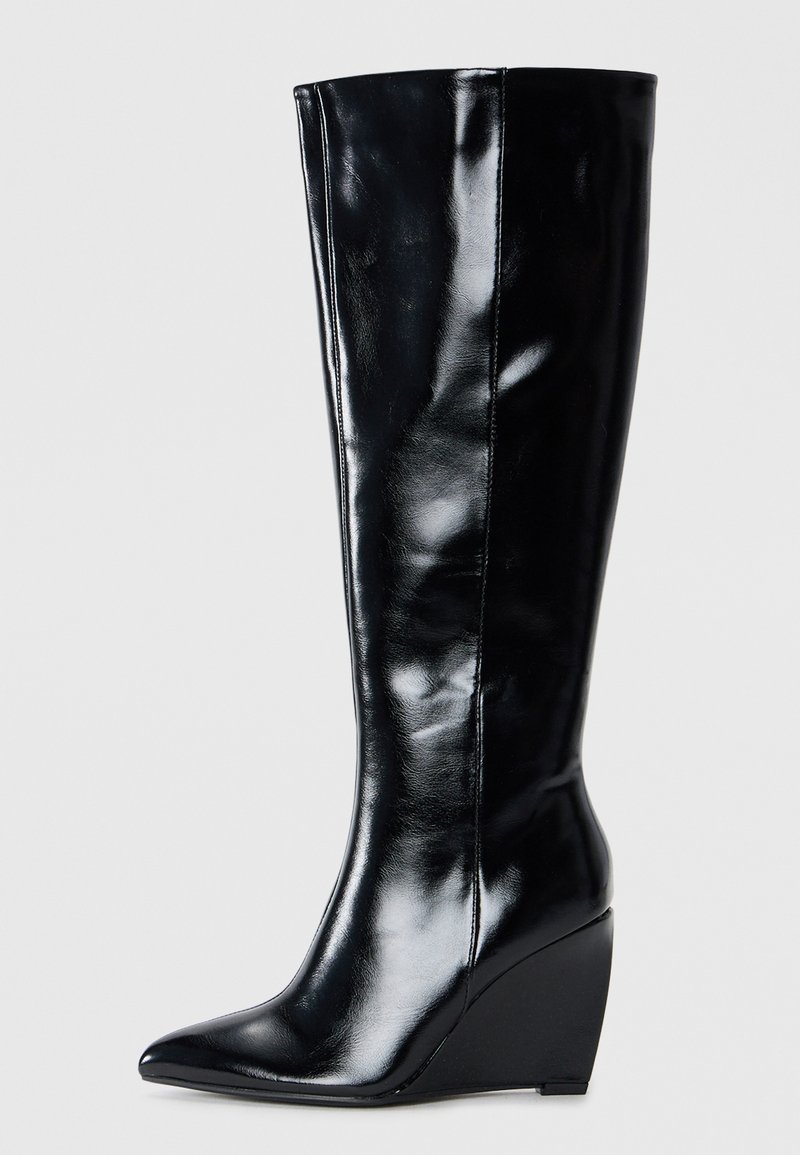 Stivali in pelle nera con tacco a zeppa, al ginocchio, dalla punta affilata e dalla finitura liscia, caratterizzati da un design elegante e affusolato.