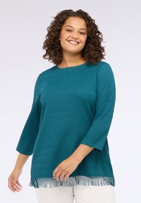 Top tricotat turcoaz cu decolteu tip barcă, mâneci trei sferturi și detalii cu franjuri la tiv. Material texturat cu mici modele ridicate.