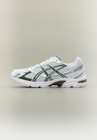 Λευκό αθλητικό παπούτσι με ύφασμα διχτυού στο πάνω μέρος, πράσινες λεπτομέρειες και γκρι διακοσμητικά στοιχεία. Διαθέτει μαξιλαρωμένη σόλα και στρογγυλεμένη μύτη για άνεση.