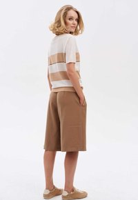 Losse beige shorts en gestreepte top in crème en bruin met een textuurpaneel. Korte mouwen en zakken in de shorts.