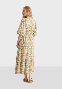 Robe maxi avec des manches bouffantes, imprimé floral en rose et vert, taille cintrée, jupe en couches et tissu léger. Portez-la avec des sabots en bois.