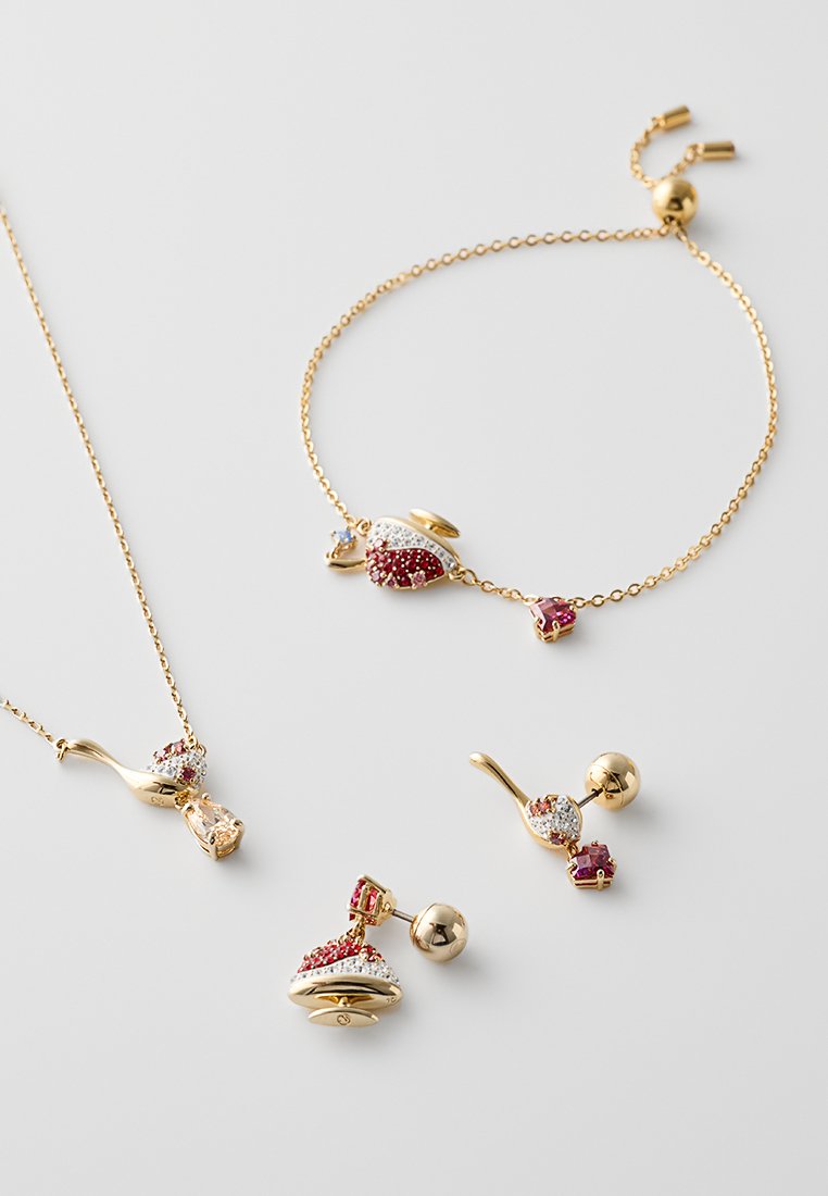 Goudkleurige sieradenset bestaande uit een ketting, armband en oorbellen, versierd met rode en witte stenen en unieke, gebogen ontwerpen.