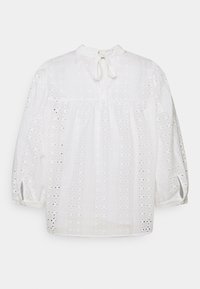 Blouse blanche en tissu texturé avec des motifs en œillets, manches longues bouffantes, taille froncée et un détail noué au niveau du col.