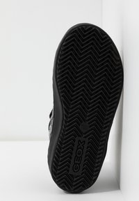 SVART sneaker sula med en texturerad fiskbensmönster och GEOX-logotyp. Rundad tå med en platt design, tillverkad av hållbart gummimaterial.