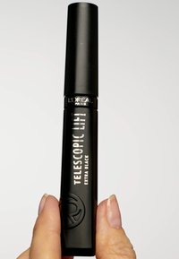 Tube de mascara noir avec un capuchon effilé, étiqueté "Telescopic Lift Extra Black" en lettres blanches, avec un logo circulaire en relief.