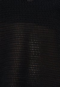 Tissu en maille noire avec de petits trous également espacés formant un motif en quadrillage et de légères variations de texture sur toute la surface.