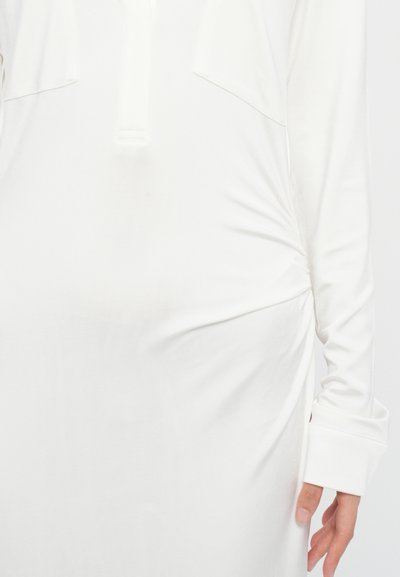 Witte jurk met lange mouwen, hoge kraag en geplooide details in de taille. Zachte, gladde stof met een ontspannen pasvorm.