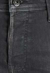 Pantalones de mezclilla negra con un diseño clásico de 5 bolsillos, botón de metal resistente y textura suave con un ligero desvanecimiento a lo largo de las costuras.