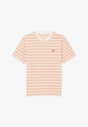 Camiseta blanca de manga corta con finas rayas horizontales naranjas y un pequeño logo verde de cocodrilo en el pecho izquierdo.