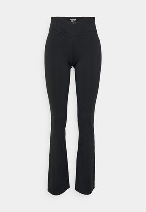 Fekete, harang szabású leggings rugalmas anyagból. Magas derekú, ferde varrás részletekkel rendelkezik. Simább textúra, látható logók nélkül.