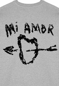 Camicia di tessuto grigio con testo stampato nero "Mi Amor" sopra una forma di cuore con una freccia attraverso, caratterizzata da un design invecchiato.