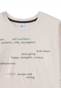 Beige t-shirt featuring printed text in various colors, displaying positive attributes. Crew neck design, soft fabric, casual style.