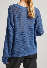 Jasnoniebieski wełniany sweter z luźnym, otwartym splotem, szerokimi rękawami i prążkowanym dołem, zapewniający swobodny krój.