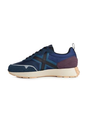 Scarpa sportiva blu navy realizzata in materiali scamosciati e in rete, con un design incrociato nero a contrasto e un accento viola sul tallone. Suola in gomma con grip testurizzato.