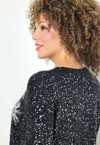 Maglione nero con motivo a macchie argento e dettaglio a fiocchi di neve. Presenta un collo rotondo e una vestibilità rilassata. Tessuto a maglia morbido.