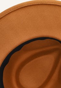 Bruine vilten hoed met een brede rand, voorzien van een zwarte binnenband en een gladde textuur. De rand buigt omhoog, wat een onderscheidende vorm creëert.