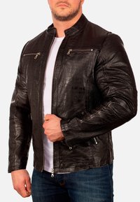 Zwart leren jack met een krokodillenstructuur, voorzien van een staande kraag, een rits aan de voorkant en twee borstzakken met metalen accenten.