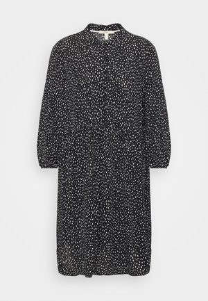 Robe noire avec un col, des manches bouffantes trois-quarts et un motif à pois blancs, avec une taille froncée. Tissu doux.