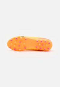 Suela de botas de fútbol en un vibrante color naranja con tacos rosas. Presenta una superficie texturizada y un logotipo grabado en la suela para ofrecer tracción.