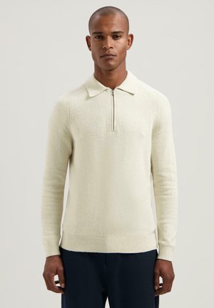 Lichtcrème pullover, ritskraag, gestructureerd breiwerk, geribbelde mouwen en zoom, lange mouwen, getailleerd silhouet, zacht materiaal, minimalistisch ontwerp.