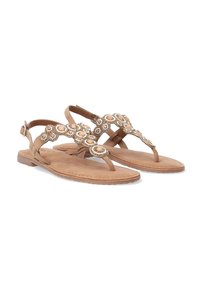Braune Sandalen mit einem dekorativen Riemen und kreisförmigen Verzierungen. Sie bestehen aus weichem Material, haben eine flache Sohle und einen verstellbaren Knöchelriemen.