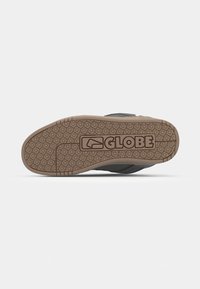 Black skate shoe sole with textured brown rubber, featuring a geometric pattern and "GLOBE" logo prominently displayed.