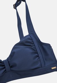 Navy blauwe bikini top gemaakt van gladde stof met een gerimpeld ontwerp en brede bandjes, met gouden hardware aan de zijkant.
