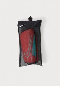 Nike Mercurial red shin guards in a black mesh storage bag. Features green accents and a logo, designed for comfort and protection.