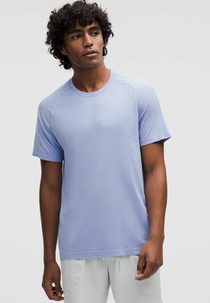 Jasnoniebieski t-shirt z krótkim rękawem, wykonany z fakturowanej tkaniny, z okrągłym dekoltem oraz kontrastowymi szwami na ramionach i rękawach.