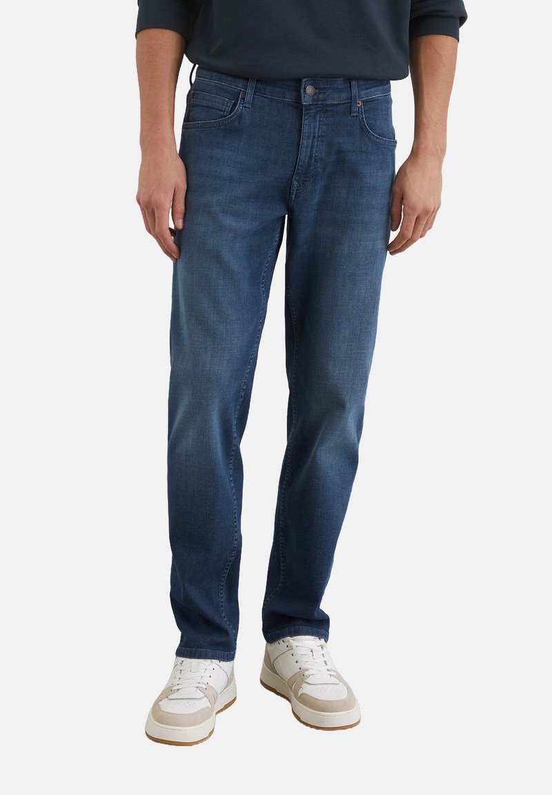 Jeans da uomo in denim di cotone, design a gamba dritta, finitura sbiadita, cinque tasche, chiusura con bottone, abbinati a sneakers bianche.