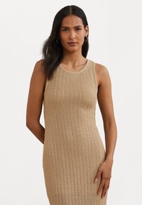 Vestido de punto, sin mangas, tipo bodycon en un tono beige claro con un patrón texturizado y escote redondo, ajuste entallado y detalles de canalé sutiles.