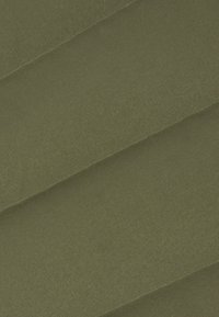 Mørke olivengrønt stof med en glat tekstur, der har diagonale folder og en subtil glans. Materialet virker blødt og slidstærkt.