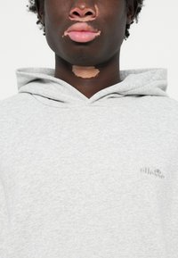 Sweatshirt cinza feito de tecido macio com um acabamento texturizado, apresentando um pequeno e discreto logotipo no peito e um capuz com cordão.