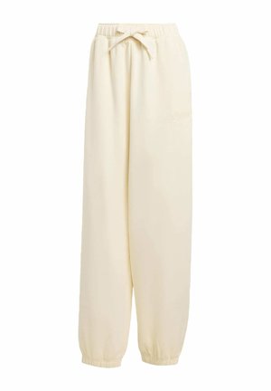 Pantalones de chándal sueltos color beige, fabricados en material suave. Cuentan con una cinturilla elástica con cordón y puños elásticos en los tobillos.