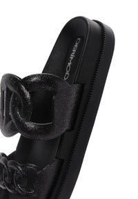 Sandalias de plataforma negras con amplios eslabones de cadena brillantes. Textura suave y sutil detalle de brillo en las correas. Logotipo de la marca en la plantilla.