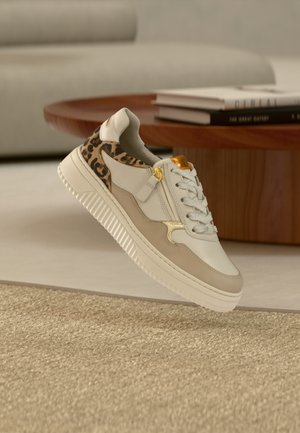 Sneakers met een witte leren bovenkant, beige accenten en een hak met luipaardprint. Voorzien van een gestructureerde buitenzool en gouden hardware detail.