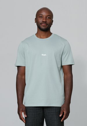 Helles mintgrünes T-Shirt mit kurzen Ärmeln aus weichem Stoff, das an der Vorderseite einen weißen Aufdruck mit dem Text "Nope." hat.