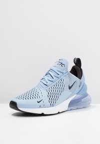 Light blue Nike Air Max sneakers featuring a mesh upper with a black accent, white sole, and transparent air cushioning in the heel.