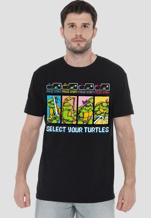 Schwarzes Baumwoll-T-Shirt mit einem Grafikdesign aus einem Retro-Videospiel, das vier Cartoon-Schildkröten zeigt. Der Text lautet "WÄHLE DEINE SCHILDKRÖTEN" in Blau.