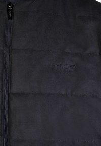 Navyblaue Steppjacke aus weichem, aufgerautem Stoff. Verfügt über einen Reißverschluss und ein dezentes, geprägtes Logo auf der Brust. Horizontales Nähmuster.