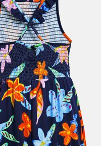 Bloemenjurk met een marineblauwe achtergrond en levendige meerkleurige bloemen, smocked buste en gekruiste rugbandjes.