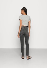 Gray cropped top with smocked texture, paired with dark gray fitted jeans. Black and leopard print sandals complete the outfit.