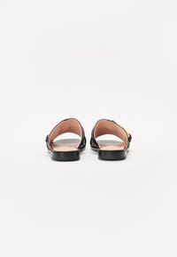 Sorte sandaler med åpen tå, glatt skinn øvre del og innersåle, flat såle, sidepynt, avrundede kanter, minimalistisk design.
