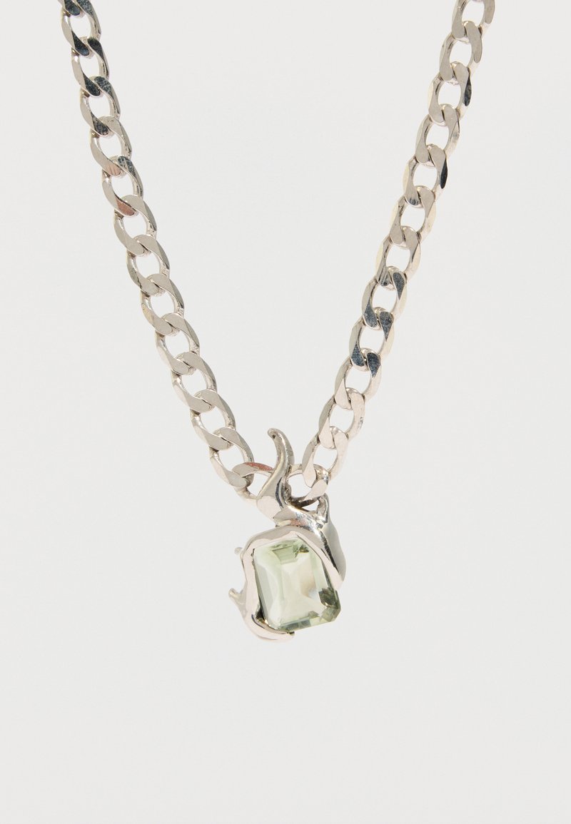 Sudraba kaklarota ar taisnstūrveida gaiši zaļu dārgakmeni kulonā, kas ietverts dekoratīvā aizdvarā. Ķēde sastāv no gludām, pulētām saitēm.